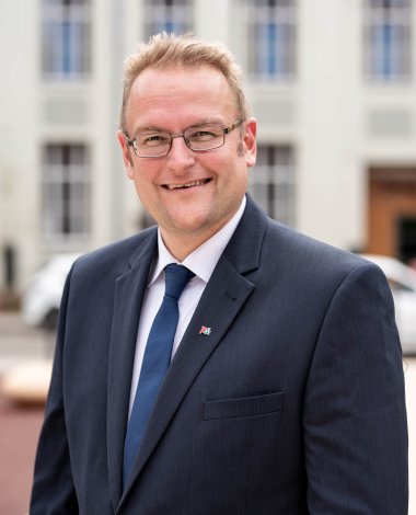 Portraitfoto von Oberbürgermeister Markus Zwick im Atrium des Dynamikum im schwarzen Anzug