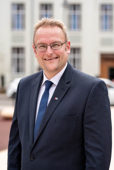 Portraitfoto von Oberbürgermeister Markus Zwick im Atrium des Dynamikum im schwarzen Anzug